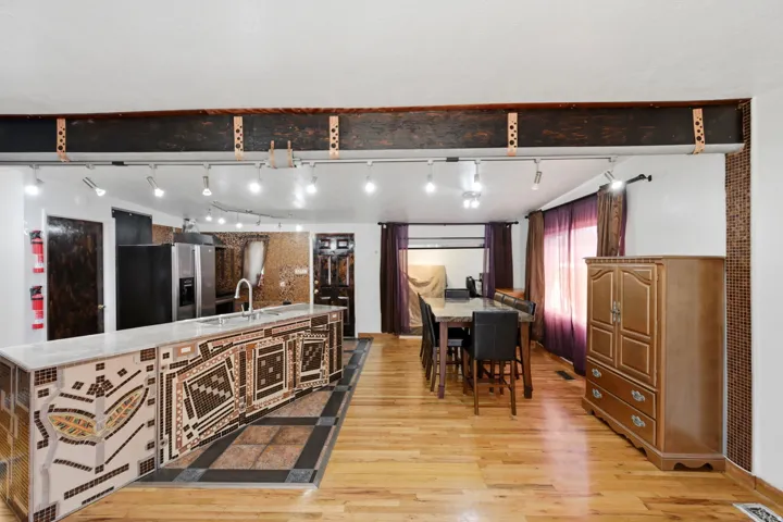 Kitchen island with an integrated sink and mosaic tile detailing, wood-finish flooring, and recessed track lighting