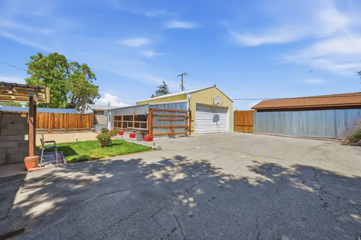 Expansive paved area with a detached garage and a separate structure with a metal roof