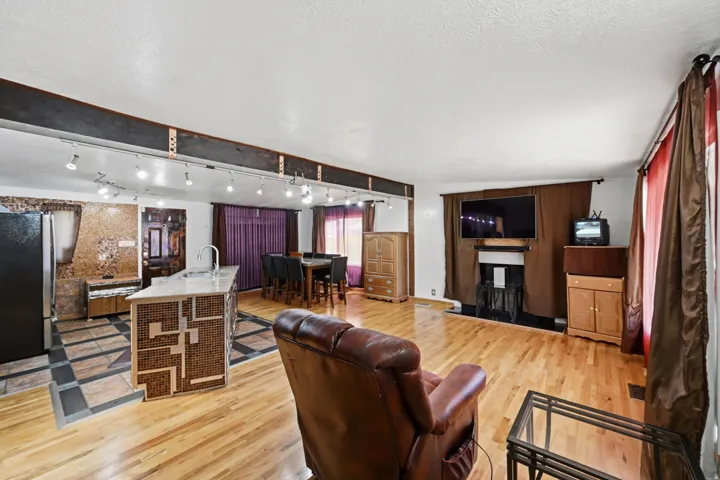Hardwood flooring throughout, kitchen island with integrated sink, recessed ceiling lighting, built-in fireplace, and expansive windows