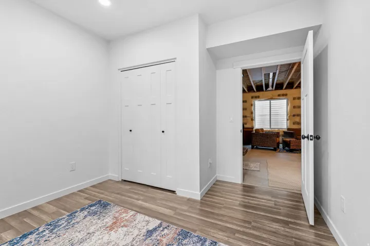 Recessed ceiling lighting, wood-finish flooring, white bi-fold closet doors with black hardware, and a white interior door with black hardware