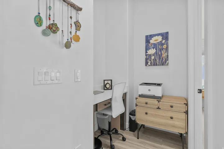 Wood-finish flooring, built-in desk with a light-toned countertop, and white walls