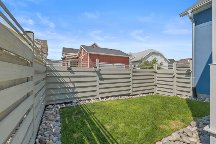 Private fenced yard with manicured lawn and decorative river rock borders