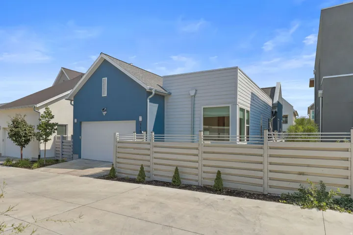 Modern exterior featuring blue and light gray siding, an attached garage, a contemporary horizontal slat fence, and concrete driveway