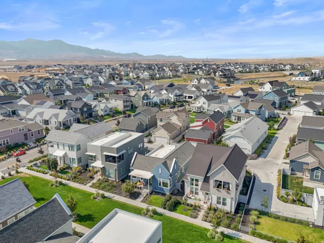 Expansive residential area with diverse architectural styles, landscaped common areas, and distant mountainous terrain