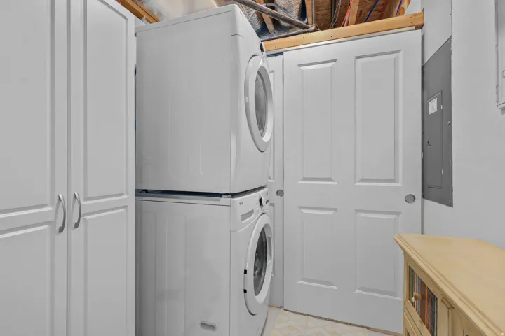 Built-in tall cabinetry with double doors, stacked washer and dryer, and a white paneled door