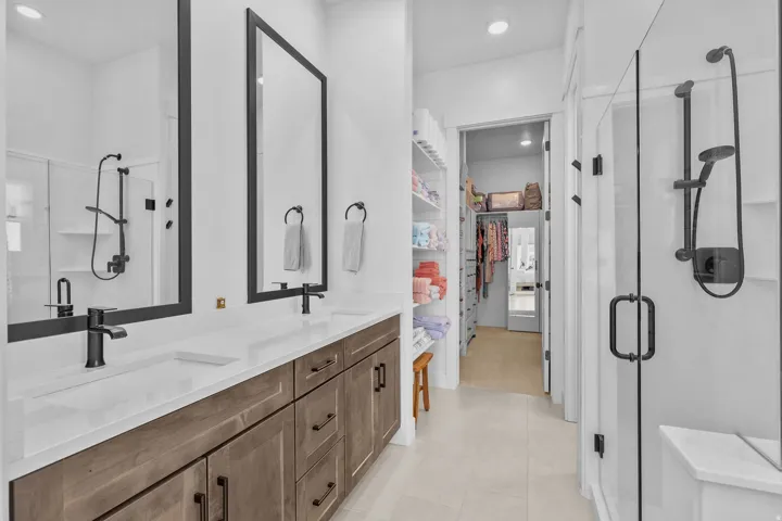 Dual vanity with white countertops, wood-finish cabinetry, and matte black fixtures