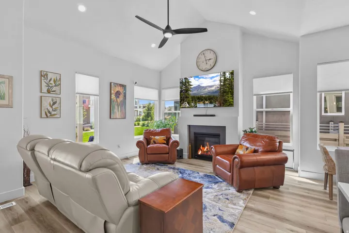 Living area featuring vaulted ceilings, wood-finish flooring, a contemporary fireplace with a sleek surround, and recessed lighting