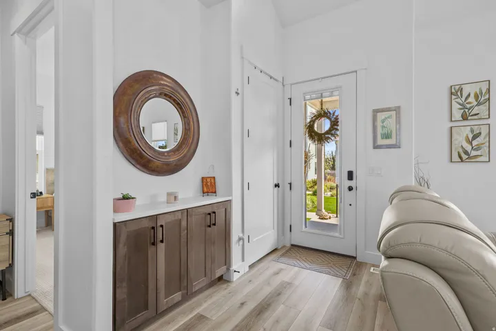 Wood-finish flooring, built-in storage cabinet with a light-colored countertop, and a white front door with a glass insert