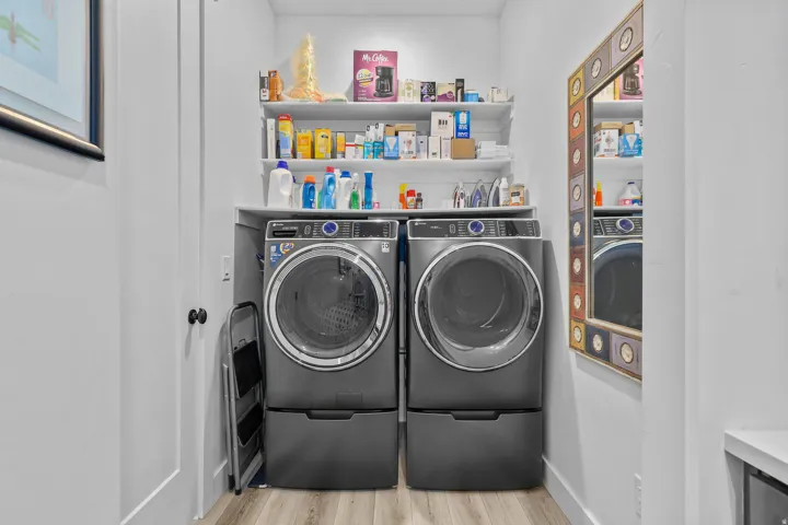 Laundry area with wood-finish flooring, built-in shelving, and white walls
