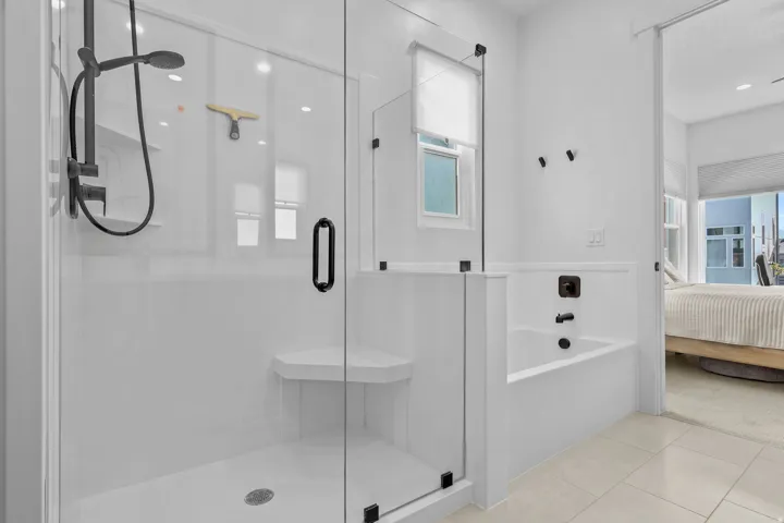 Glass-enclosed shower with matte black fixtures, integrated shelving, and a built-in bench