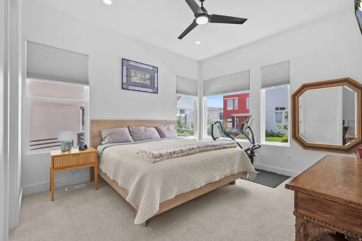 Recessed ceiling lights, a black ceiling fan, and multiple windows with cellular shades