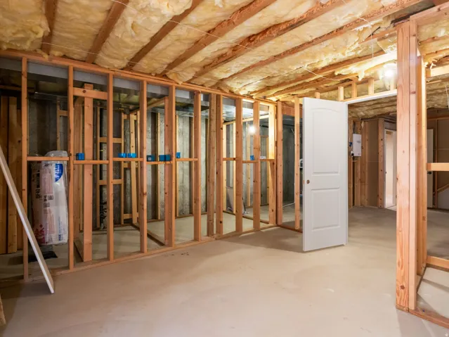 Unfinished basement with exposed wood framing, concrete flooring, and ceiling insulation