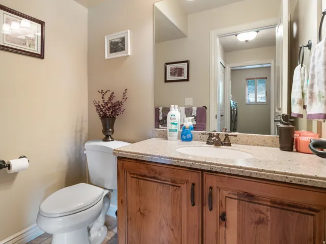 Half bathroom on main level. Vanity with a granite-style countertop, undermount sink, and wood-finish cabinetry.