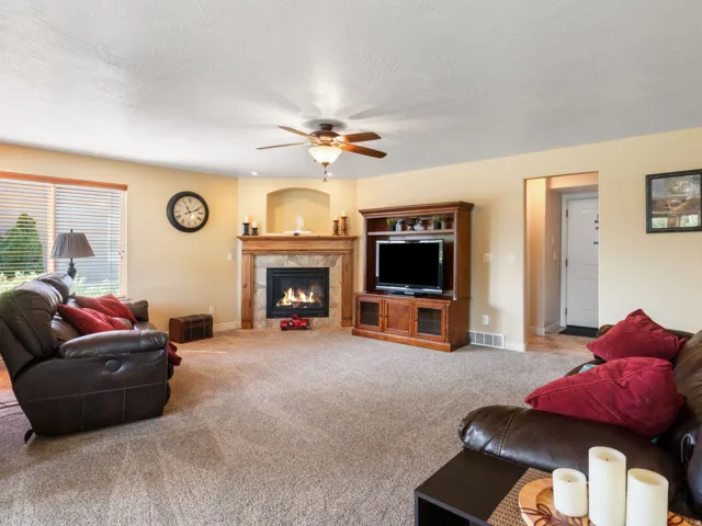 Carpeted living area featuring a fireplace with a stone surround and wood mantel.