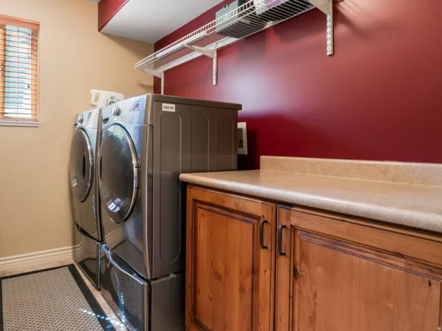 Laundry area with wood-finish cabinetry, light-toned countertop, and overhead wire shelving.