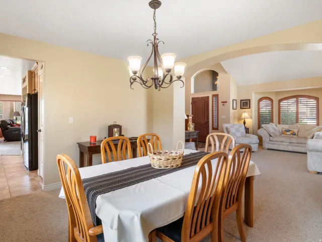 Formal Dining area connected to formal living area. With carpeted flooring, featuring a five-light chandelier