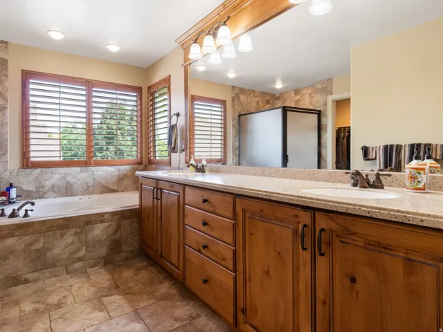 Primary En-suite. Expansive dual vanity with wood cabinetry, light-toned countertop, and integrated sinks