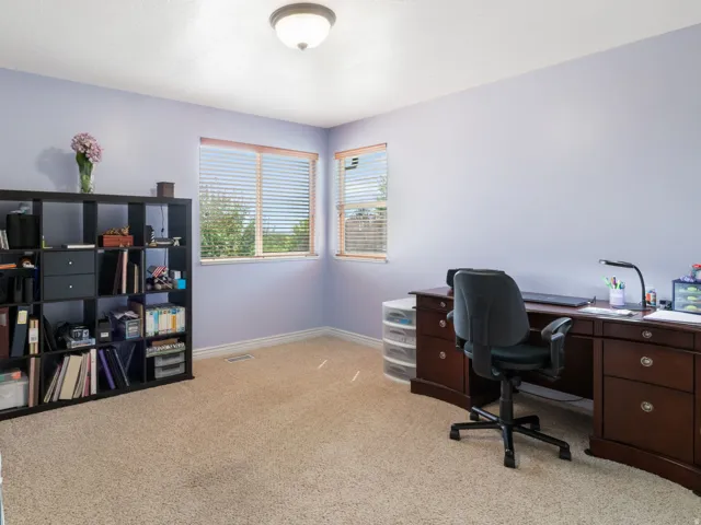 Additional bedroom 3 used as home office. Carpeted room with light purple walls, two windows, and a flush-mount ceiling light