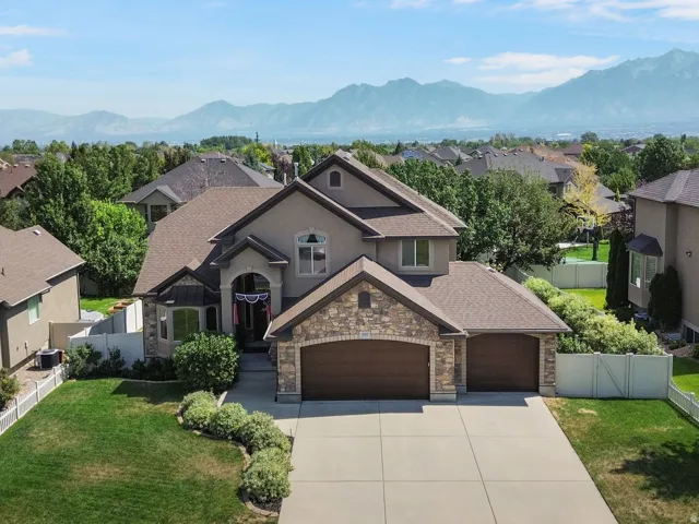 Two-story residence with a stone and stucco exterior, an attached three-car garage, and a concrete driveway.