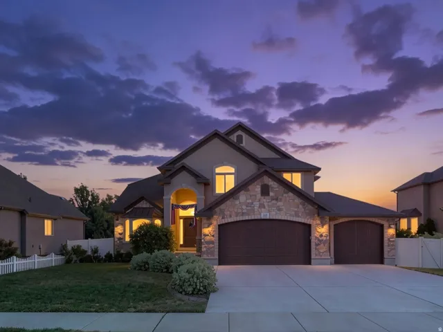 Stucco exterior with stone accents, arched entryway, and dual garage doors