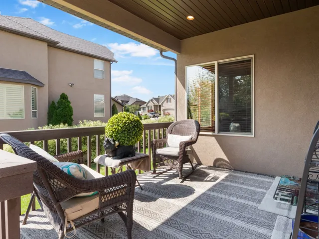 Covered outdoor patio with a textured stucco exterior, wood-finish ceiling, and durable wood railing.