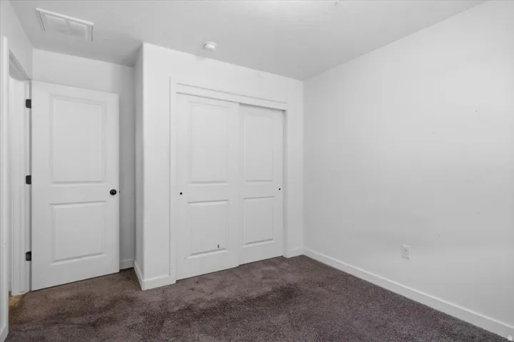 White-painted interior room featuring gray carpet flooring and white baseboards