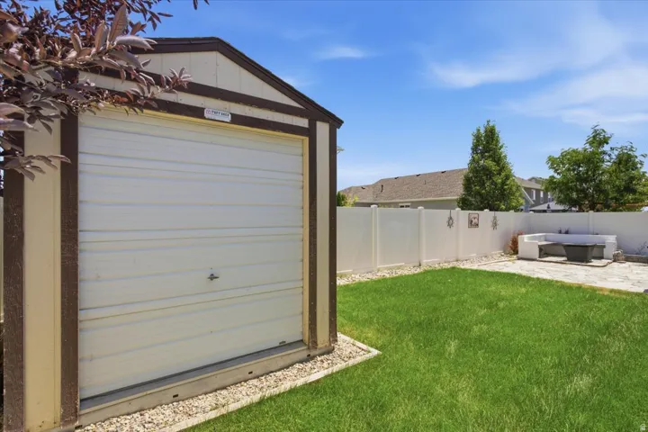 Detached storage shed featuring a rolling garage door, gravel base, and a gabled roof