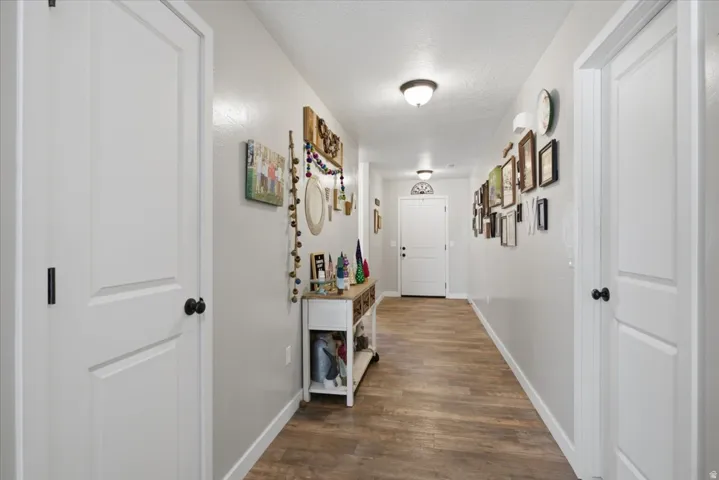Elongated hallway featuring wood-finish flooring and light gray walls