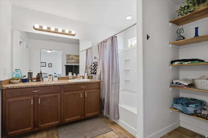 Bathroom featuring a spacious vanity with a solid surface countertop, integrated sink, and wood-finish cabinetry