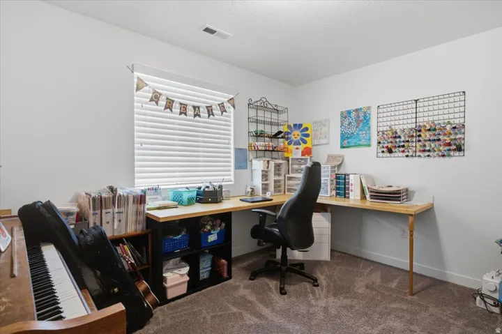Room featuring neutral wall paint, carpet flooring, a window with horizontal blinds, and a built-in desk with wood-finish surface