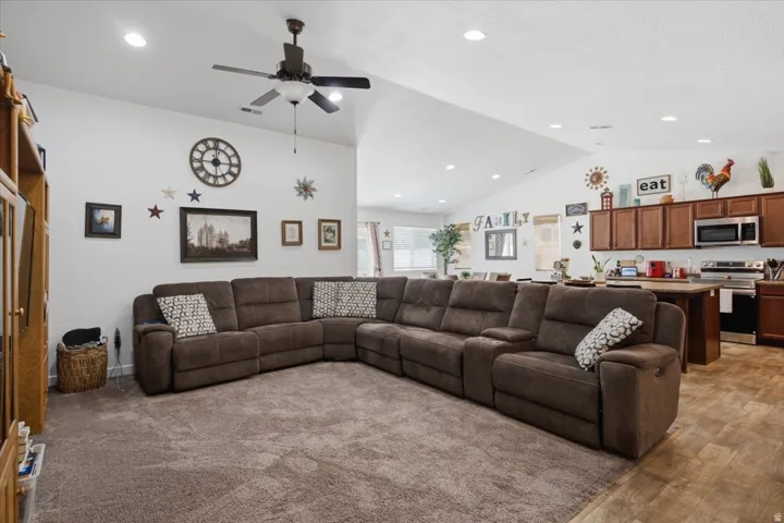 Spacious living area featuring vaulted ceilings with recessed lighting and a ceiling fan