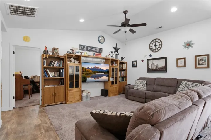 Spacious living area featuring vaulted ceilings, recessed lighting, ceiling fan, and carpet flooring