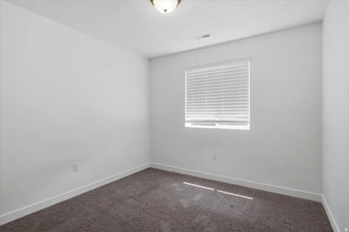 Neutral white walls with white trim and a single window with horizontal blinds