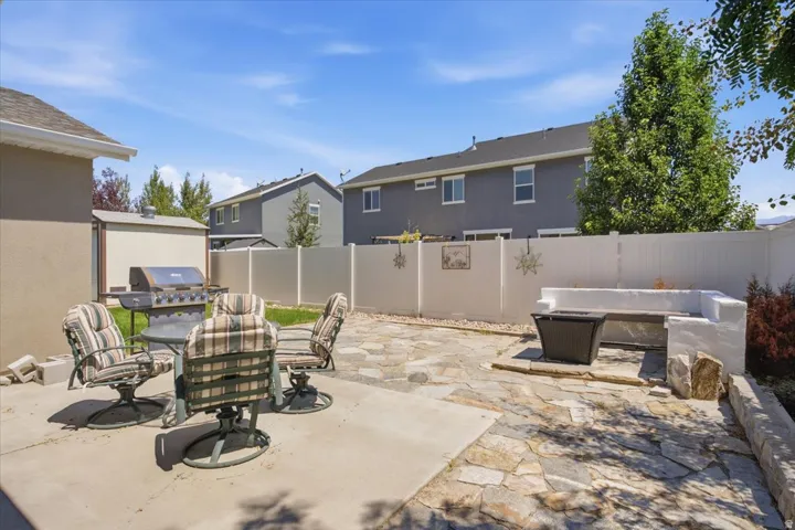 Expansive outdoor patio featuring flagstone paving, a concrete slab, a built-in bench, and a white privacy fence