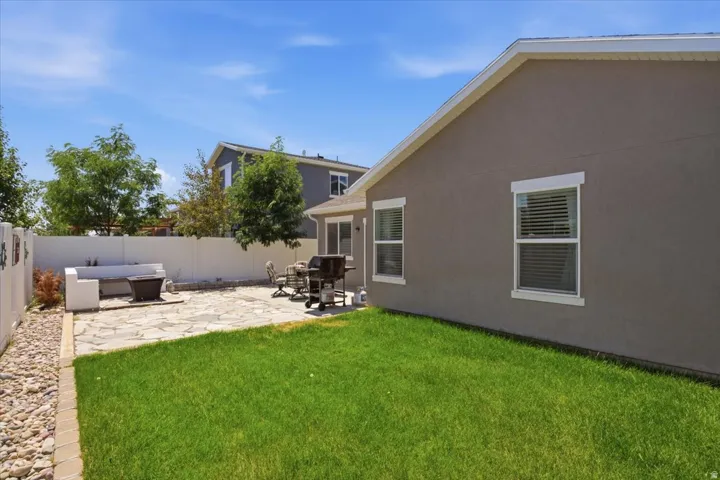Expansive backyard featuring a lush lawn, flagstone patio, privacy fencing, and a built-in bench