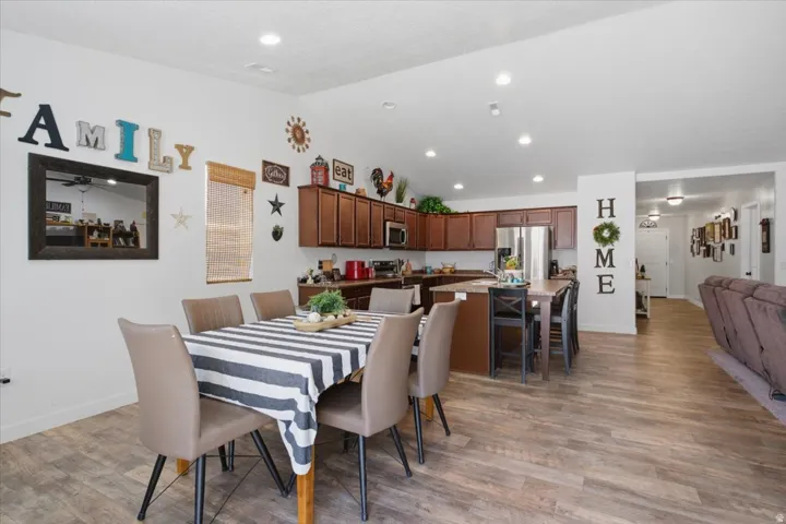 Open concept living area featuring wood-finish flooring, recessed lighting, and a spacious kitchen with dark wood cabinetry and stainless steel appliances