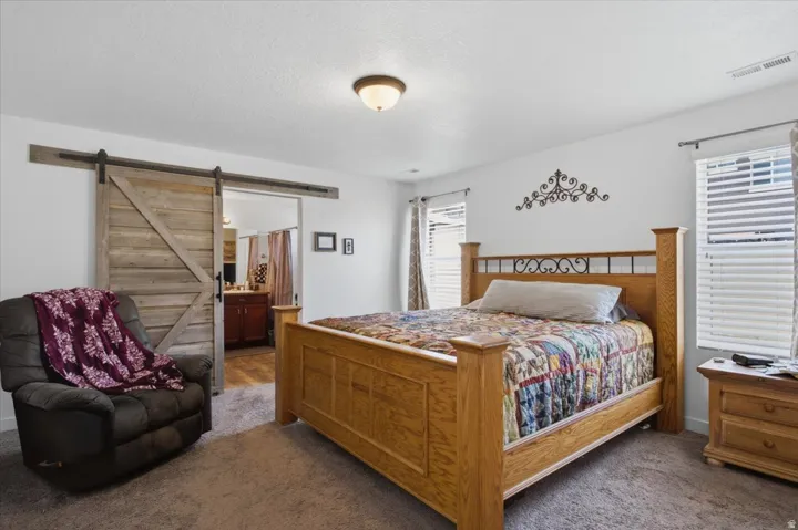 Spacious bedroom featuring neutral wall tones, carpet flooring, and dual windows with blinds