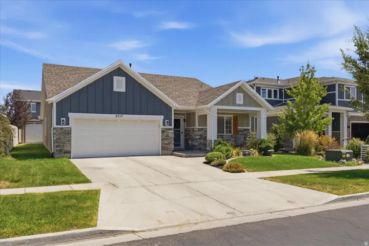 Contemporary ranch-style home featuring stone veneer accents, vertical blue siding, and a two-car garage