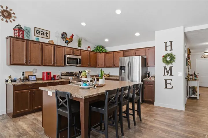Kitchen featuring an oversized island with counter seating, extensive brown cabinetry, stainless steel appliances, and recessed lighting