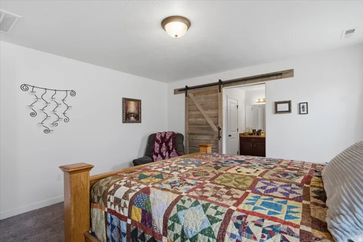 Bedroom featuring a sliding wood barn door entrance to an en-suite bathroom