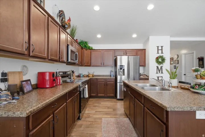 Galley-style kitchen featuring rich wood cabinetry, granite countertops, and stainless steel appliances including a French-door refrigerator
