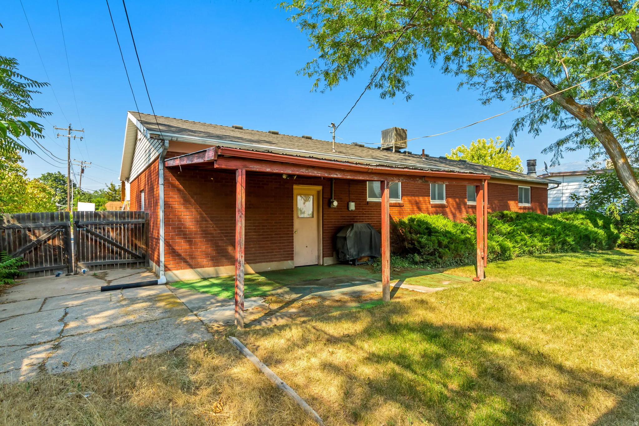 Rear exterior featuring a covered patio, brick facade, and a fenced property line