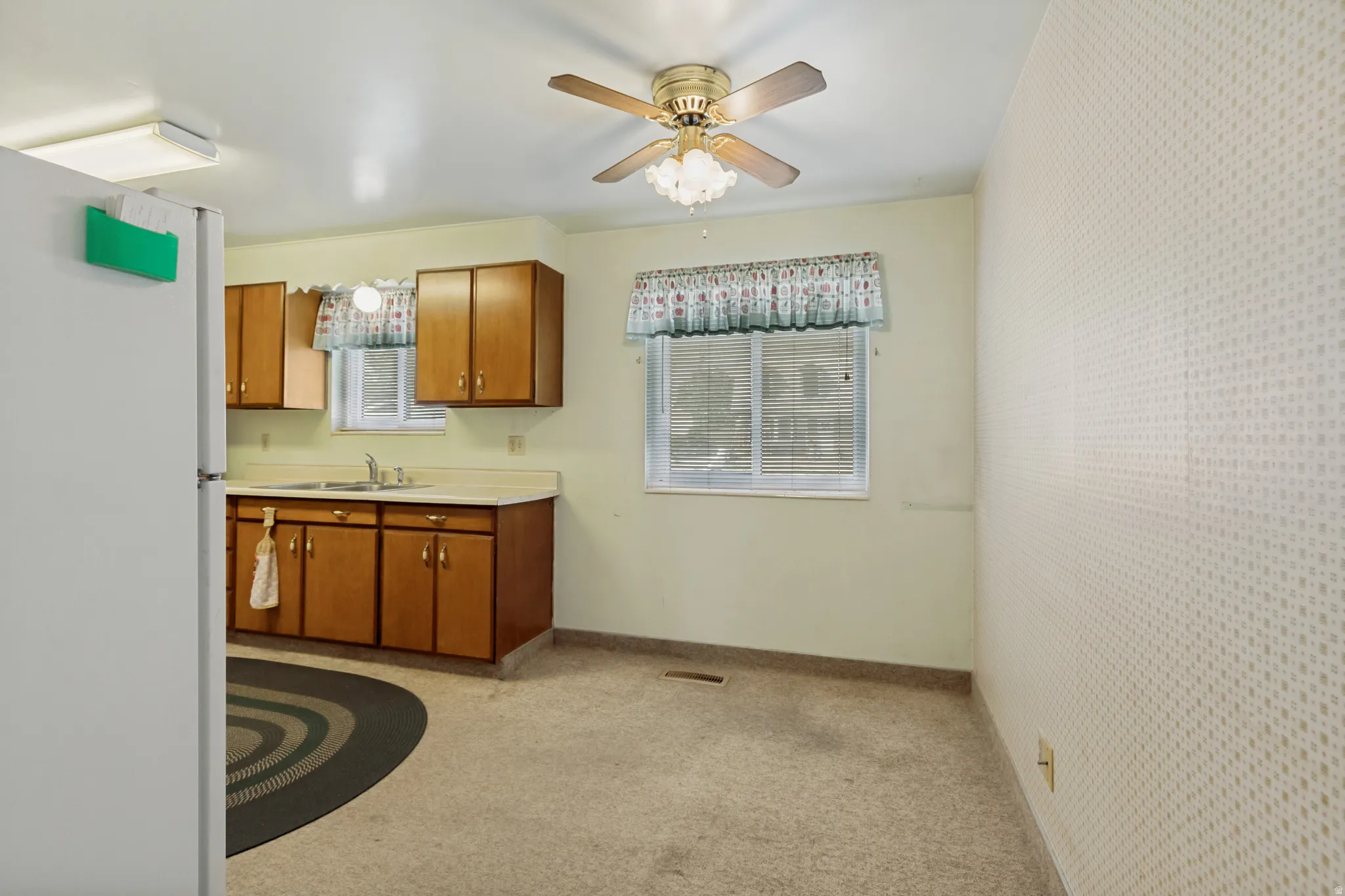 Kitchen with wood-finish cabinetry, a stainless steel sink, and a multi-speed ceiling fan with integrated lighting