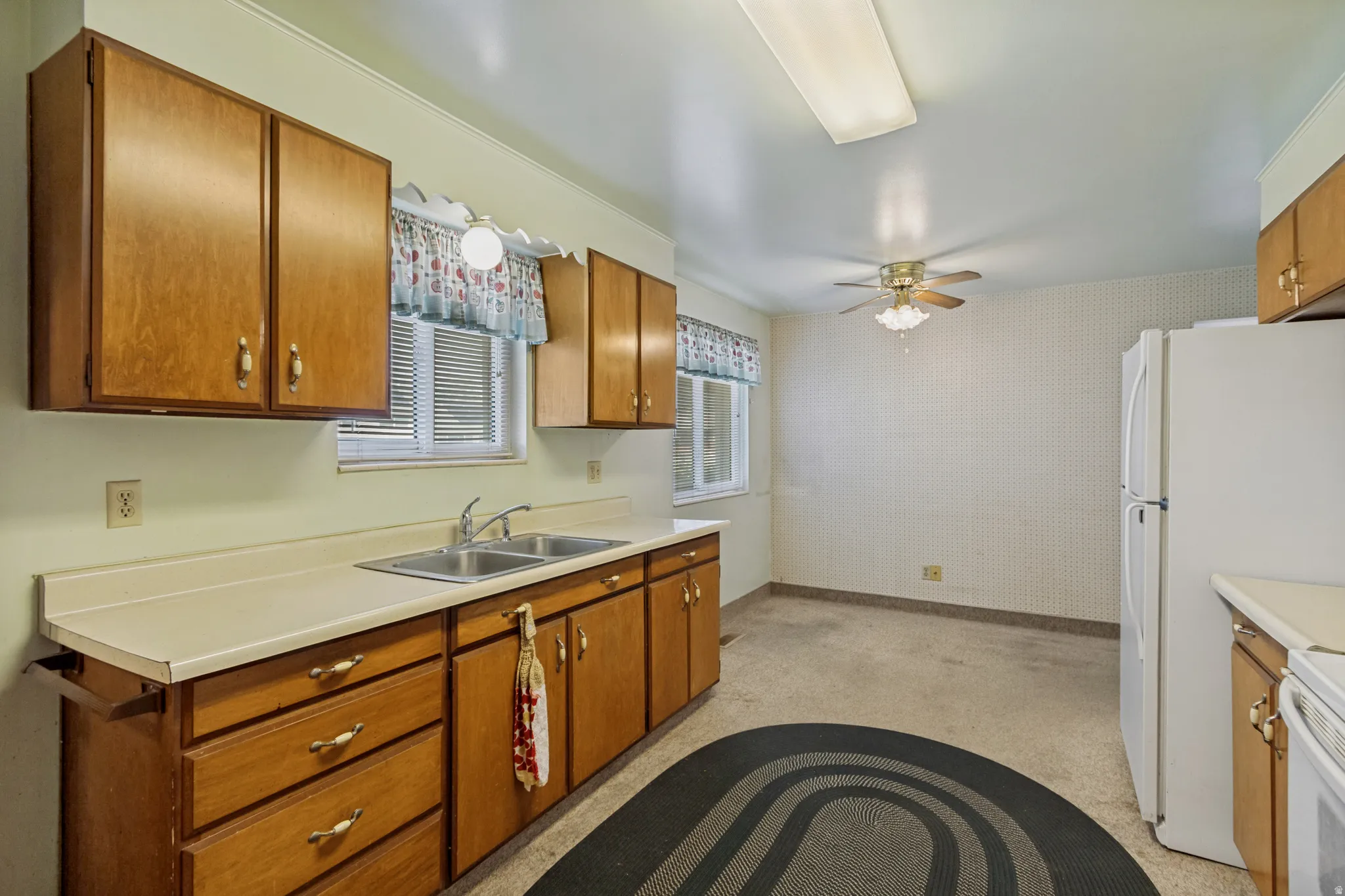Kitchen featuring wood-finish cabinetry, a dual basin stainless steel sink, and light-toned countertops