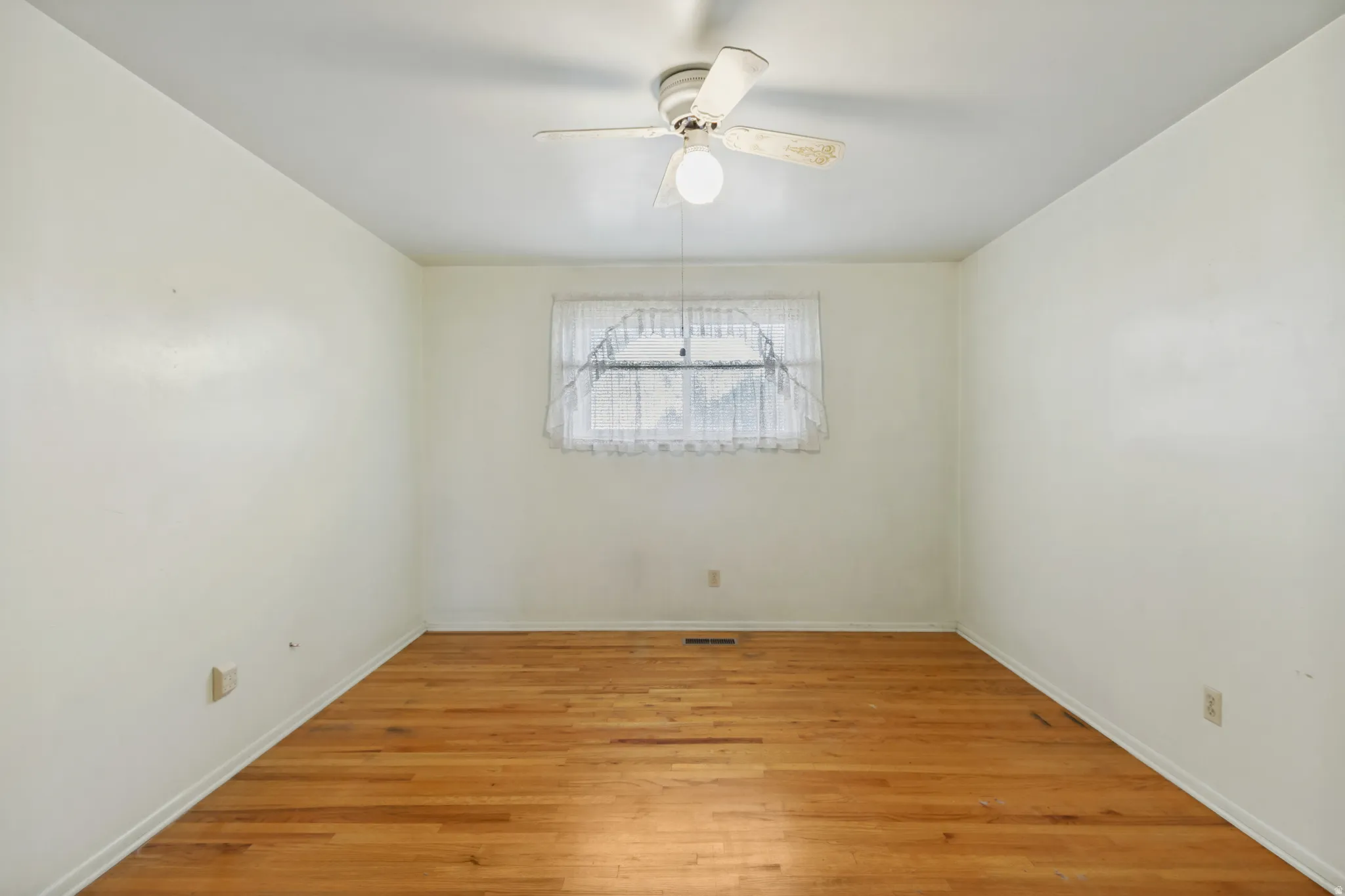 Hardwood flooring, white walls, and a ceiling fan with integrated lighting