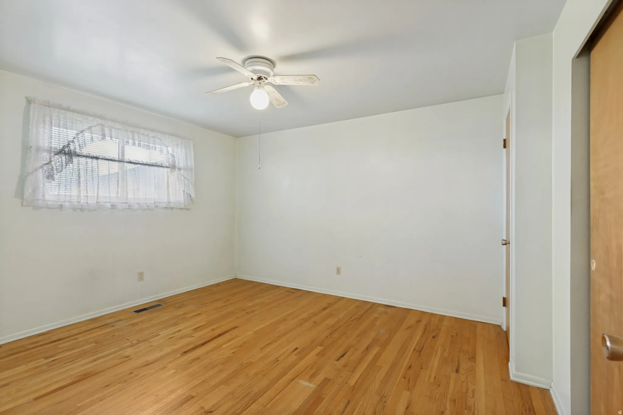 Wood-finish flooring, white walls, and an overhead ceiling fan