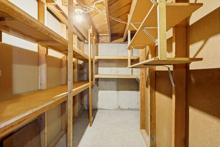 Extensive built-in shelving, exposed wood framing, concrete floor, and visible ceiling joists