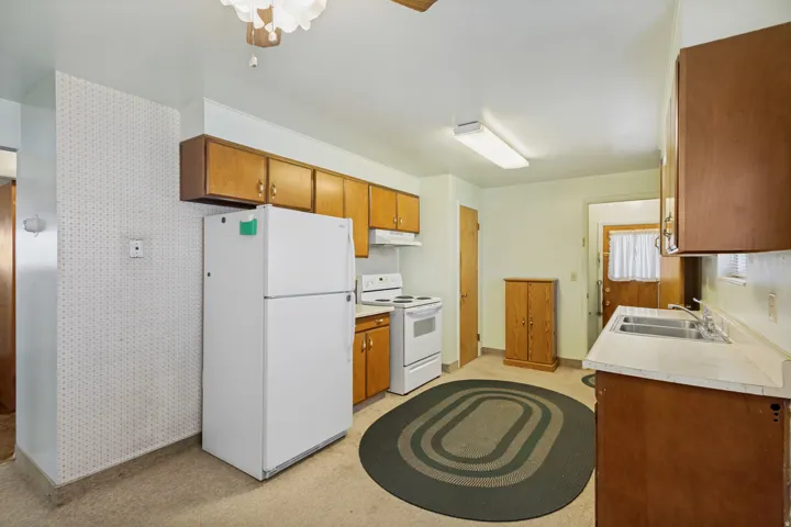 Kitchen featuring wood-finish cabinetry, white appliances, and a double-basin stainless steel sink