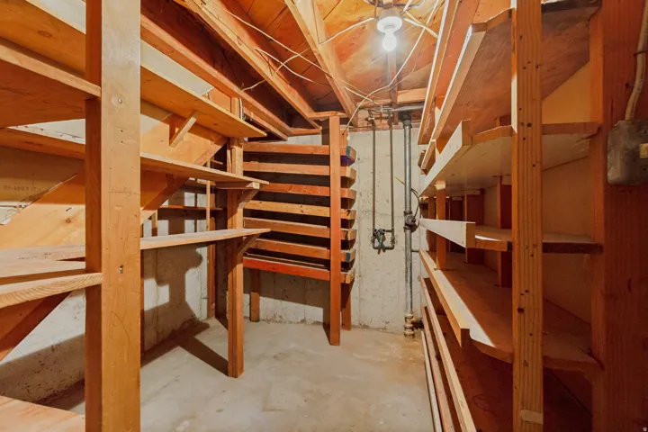 Extensive wood shelving units, concrete flooring, and exposed ceiling joists