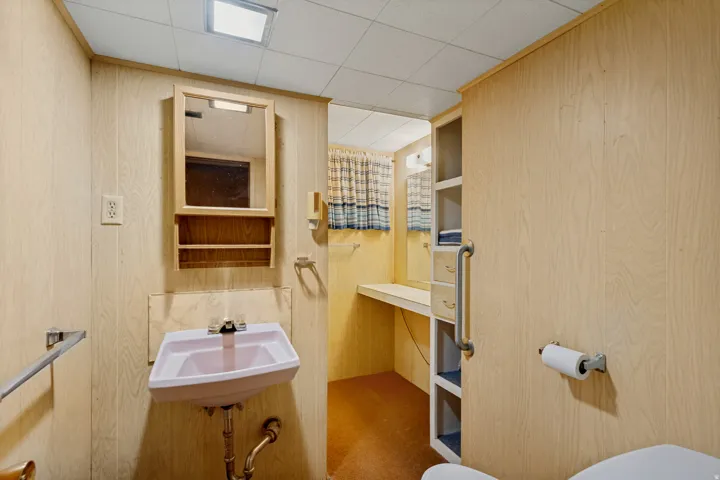 Wall-mounted sink with chrome-finish faucet, medicine cabinet, and paneling